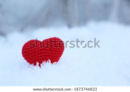 Red knitted heart on a snow in winter forest. Background for Christmas holiday, Valentine's card