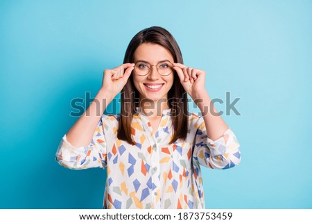 Photo of lovely girl hold eyewear beaming smiling look camera wear eyeglasses geometry print shirt isolated blue color background Royalty-Free Stock Photo #1873753459