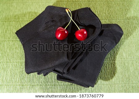 Several pairs of male socks on a green surface and red cherry