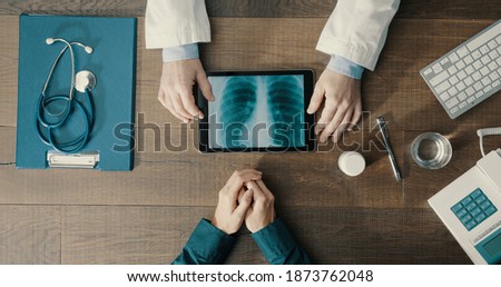 Doctor meeting a patient in the office and giving a medical consultation, he is using a digital tablet and checking medical records Royalty-Free Stock Photo #1873762048