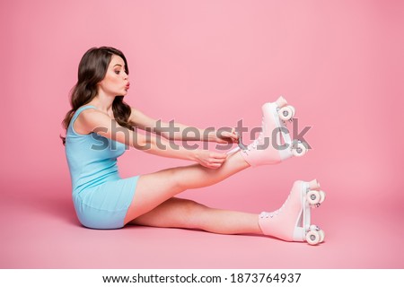 Full size side profile photo of young cute girl look copyspace sit floor pout lips tying rollers laces isolated on pink color background