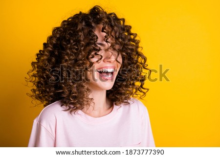 Photo portrait of girl with curly hairstyle wearing t-shirt laughing with closed eyes isolated on bright yellow color background Royalty-Free Stock Photo #1873777390