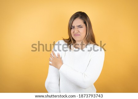 Young caucasian woman over isolated yellow background with pain on her shoulder and a painful expression