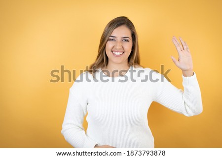 Young caucasian woman over isolated yellow background doing hand symbol