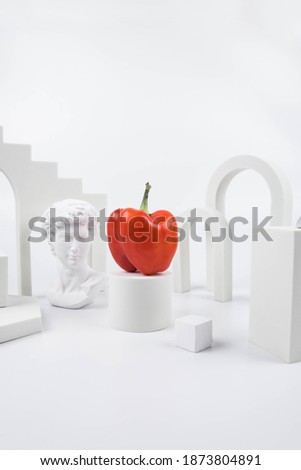 Aesthetic food photography on trendy white podium. Minimal food art still life concept.  Greek statue and sweet bell pepper on white background.