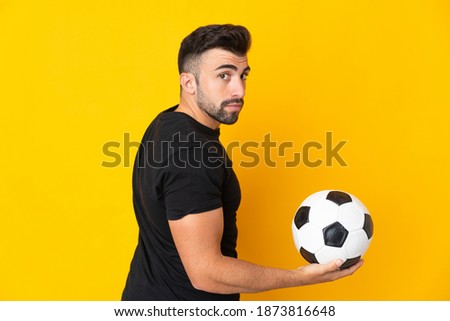 Caucasian man over isolated yellow background with soccer ball