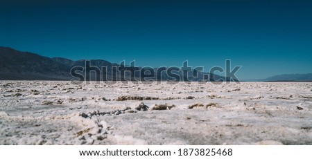 Ground level of picturesque desert with snowy rough surface located near cold hills covered with hoarfrost during sunny day of severe winter Royalty-Free Stock Photo #1873825468
