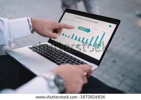 Cropped image of professional expert browsing business infographics of monetary gain on laptop computer for analyzing strategy productivity, trader pointing on web graphic charts on modern netbook