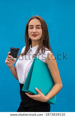 pretty young woman hold cup folder wear white shirt and black skirt isolated. 