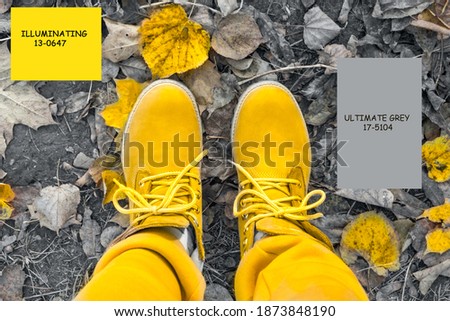 bright illuminating yellow modern boots on ultimate grey leaves in park outdoor. Colors of the year 2021, selective focus