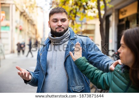 Disgruntled young woman stopping stranger man bothering her on city street.. Royalty-Free Stock Photo #1873871644