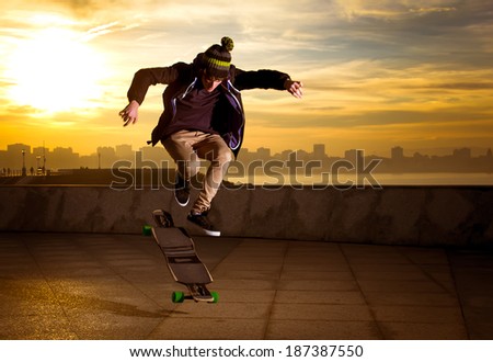 young teenager jumping with a longboard
