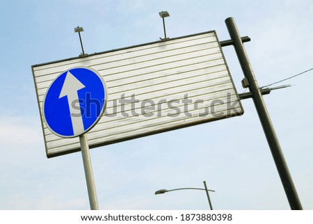 Blue traffic sign and an empty metal advertisement board.
