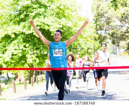 Excited male runner crossing the finshline of a marathon Royalty-Free Stock Photo #187388768