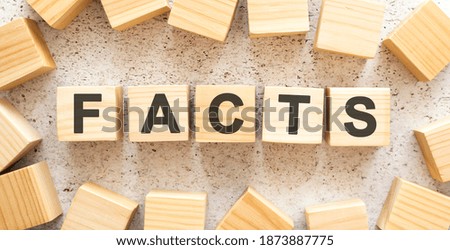 The word FACTS consists of wooden cubes with letters, top view on a light background.