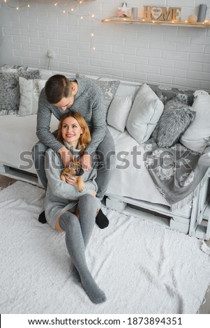 Portrait of young 35s just married couple in love posing photo shooting seated on couch in modern studio apartments, concept of capture happy moment, harmonic relationships, care and sincere feelings