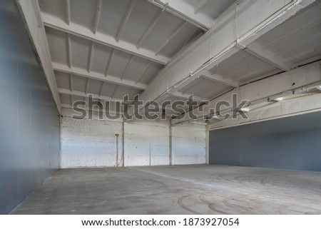 Modern interior of huge empty concrete industrial warehouse. White brick wall.