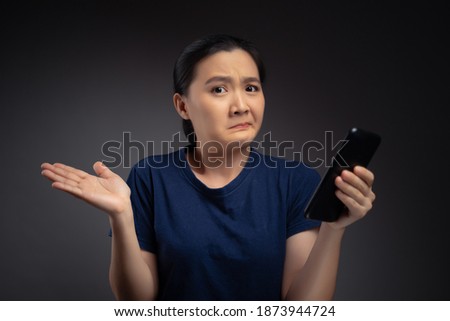 Asian woman looking at smart phone reading news and feel confused.