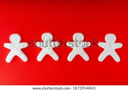  Set of cute cartoon gingerbread man cookies. Creative Holiday concept. White toys on red background. 