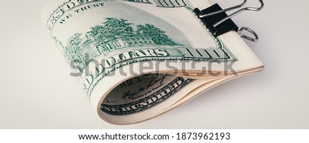 Roll of a hundred American dollars close-up on a gray background.