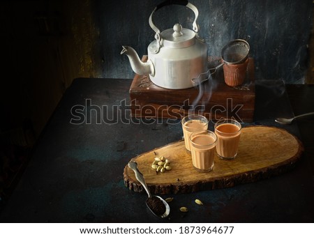 indian masala chai or tea ion ttraditional glasses, with kettle, spices and tea leaves on dark, wooden background. cafe, retro, restaurant, hotel concepts. Royalty-Free Stock Photo #1873964677