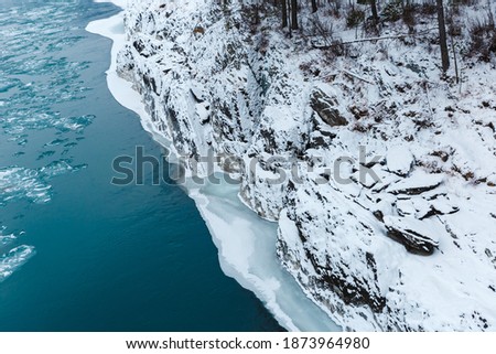 View of rocks, stones and ice in the river at winter. The trees and stones are covered with snow