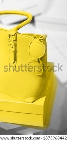 Bright illuminating yellow bag and glasses on gray color background. Concept of Color of the Year 2021. Fashion outfit abstract art layout. Front view, copy space. Valentine's day modern concept.