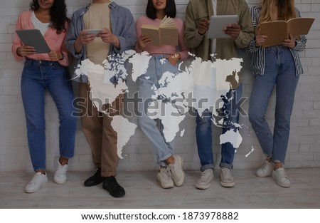 Education, international relations and student exchange. Young multiracial people with books and gadgets read, over white brick wall background, double exposure with world map, collage, cropped Royalty-Free Stock Photo #1873978882