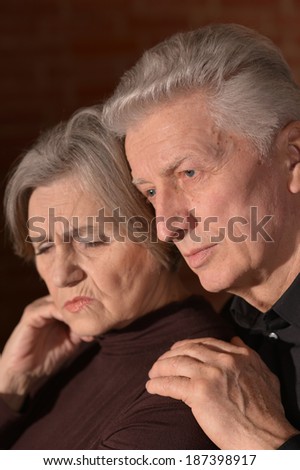 Close-up portrait of sad elder couple on a black background