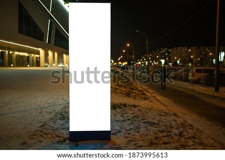 Advertising information pylon with white field glowing at night