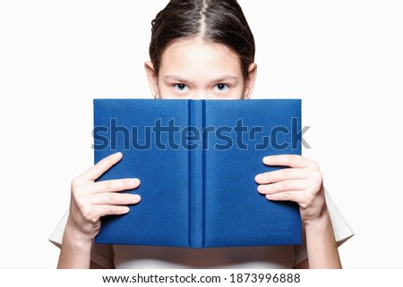 The girl covers her face with notebook