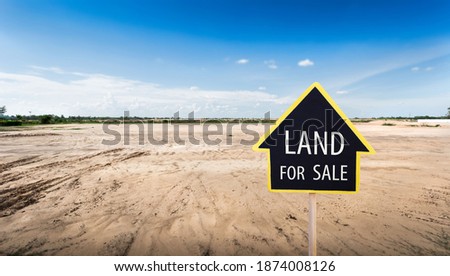 land for sale sign against trimmed lawn background. Empty dry cracked swamp reclamation soil, land plot for housing construction project in rural area and beautiful blue sky with fresh air.