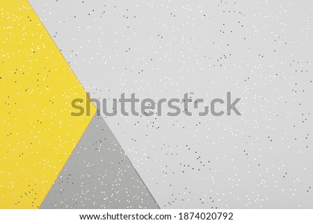 Paper background with metallic shiny stars and glitter in two trendy colors - yellow and gray. Demonstrating colors of 2021 year. Festive backdrop for your design.