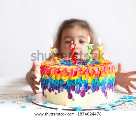 A little girl looks at a beautiful birthday cake. Birthday surprise concept