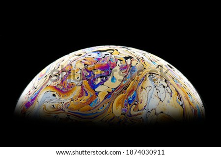 Isolate. Bright, beautiful patterns on the surface of the soap bubble. Close-up. Imitation of fantastic planets.