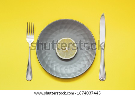 Plate with slice of lemon on yellow background. Diet concept. Colors of the year - Ultimate Gray and Illuminating.