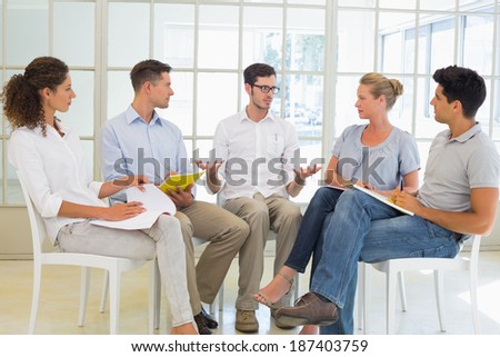 Casual business team sitting in a circle having a meeting in the office