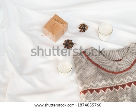 Cozy autumn or winter concept. candles, gift box with pine decoration, sweater on white background. minimal concept. top view, vintage 
