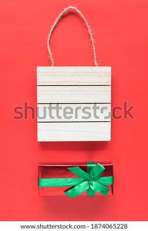 Wooden sign board frame and gift box on red background. Holiday concept.