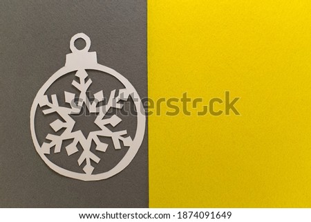 Postcard with paper cut Christmas ball on grey yellow background. Demonstrating color trend of the year 2021