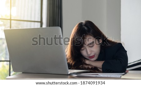 A girl tired from work fell asleep in front of the laptop on the table.