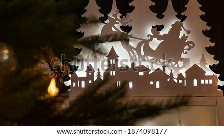 Silhouette of Santa Claus flying on a sleigh pulled by reindeer. Defocused foreground with christmas tree.