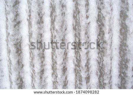 gray undulating background. It's a slightly snow-covered slate sheet. Vertical stripes