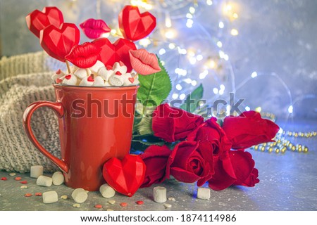 Valentine`s day sweets concept, festive holiday background with hot chocolate red cup and set of red hearts sweets on sticks in cup, with red roses and bokeh lights effect