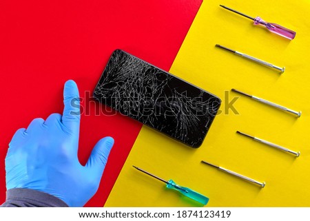 Bright color advertising banner or background for mobile phones and gadgets workshop. A black smartphone with a broken display and a lot of screwdrivers are on the table. The master's gloved finger