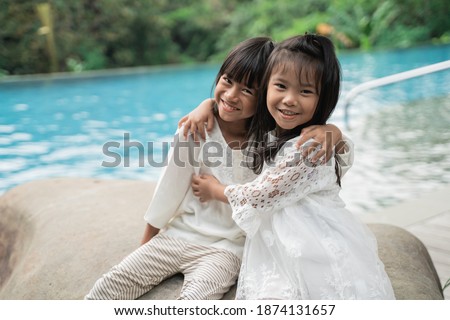 Portrait of happy sisters pictured in a swimming pool background