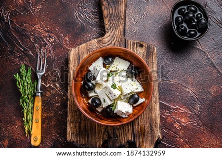 Salad with fresh feta cheese, thyme and olives. Dark background. Top view