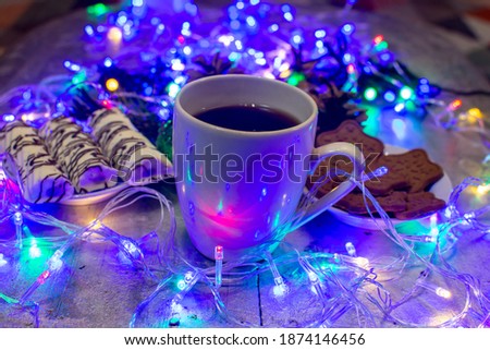Christmas composition with a mug of coffee Christmas garlands with colored lights, toys and delicious sweets