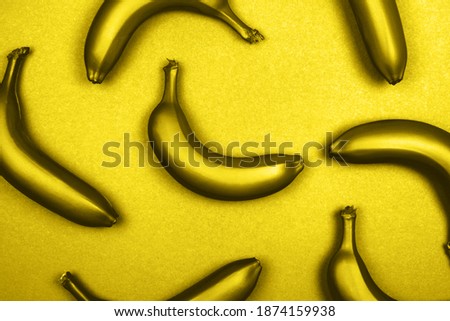 Yellow metallic bananas on monochrome background. Flat lay style. Trendy photo ispired by color of the year 2021