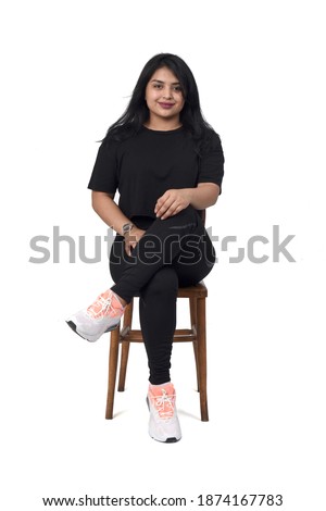 front view of a latin woman sitting on a chair legs crossed and smiling on white background,